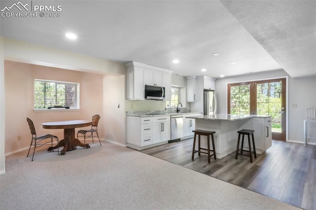 1240 Lone Scout Lookout, Monument, CO 80132 - kitchen with appliances with stainless steel finishes, a center island, a kitchen breakfast bar, white cabinets, and recessed lighting