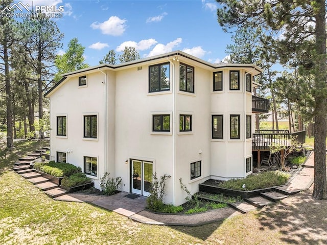 1240 Lone Scout Lookout, Monument, CO 80132 - view of home's exterior featuring stucco siding, a balcony, a yard, and a wooden deck