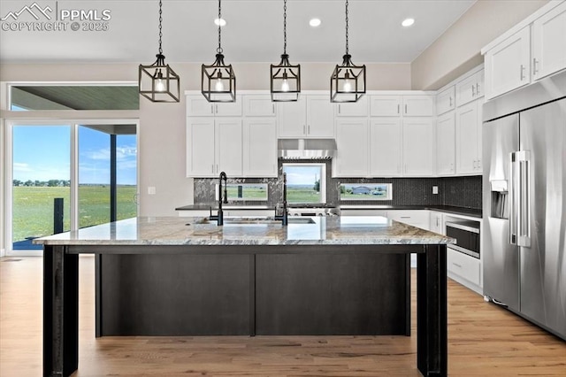 8545 Bailiff Dr, Peyton, CO 80831 - kitchen featuring stainless steel built in fridge, backsplash, light stone countertops, white cabinetry, and recessed lighting