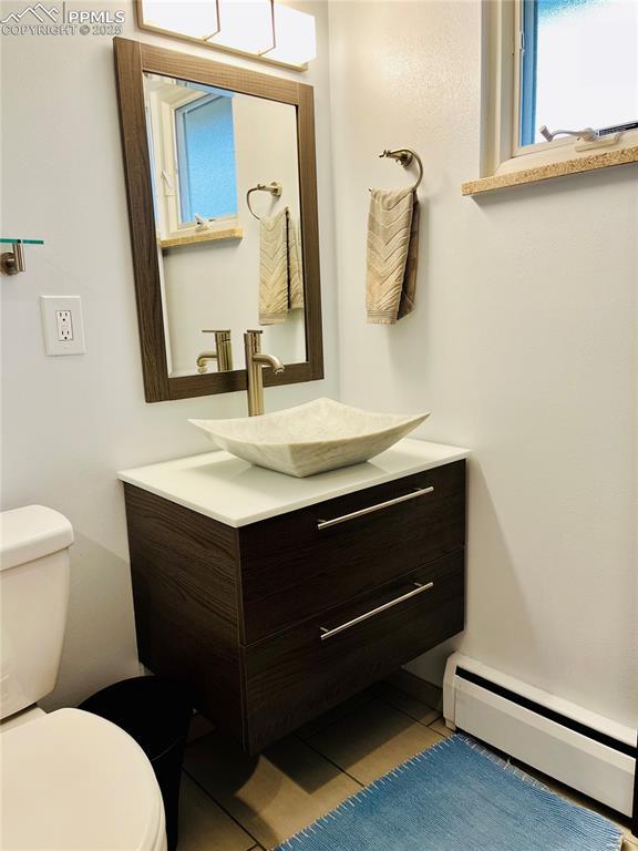 2206 Patrician Way, Colorado Springs, CO 80909 - half bath featuring a baseboard radiator, toilet, and vanity