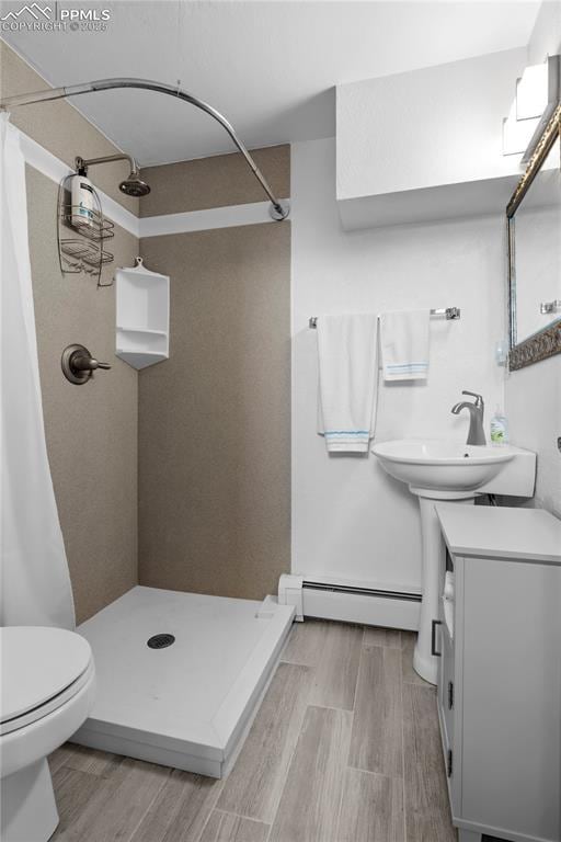 2206 Patrician Way, Colorado Springs, CO 80909 - bathroom with a baseboard radiator, a shower stall, vanity, wood finished floors, and toilet