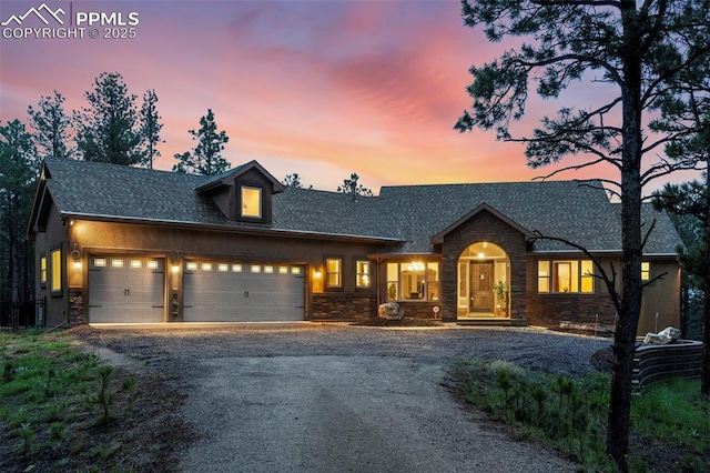 8395 Bar X Ter, Colorado Springs, CO 80908 - view of front of property with stone siding, a garage, driveway, and roof with shingles