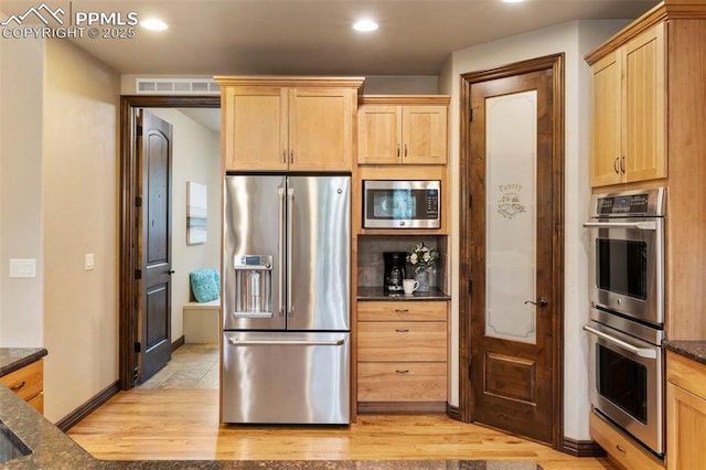 8395 Bar X Ter, Colorado Springs, CO 80908 - kitchen featuring appliances with stainless steel finishes, light wood finished floors, light brown cabinetry, dark stone counters, and recessed lighting