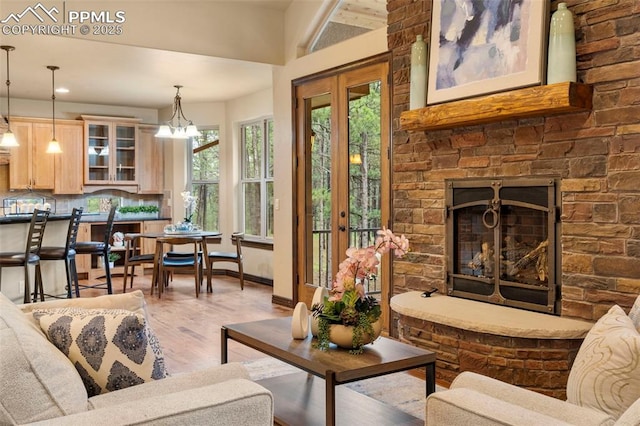 8395 Bar X Ter, Colorado Springs, CO 80908 - living room with light wood-style flooring, a stone fireplace, baseboards, a chandelier, and recessed lighting