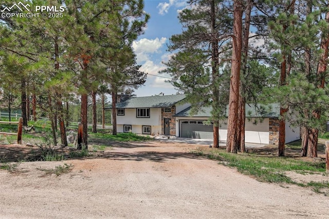 4580 Creek View Rd, Colorado Springs, CO 80908 - view of front facade with dirt driveway, stone siding, stucco siding, and an attached garage