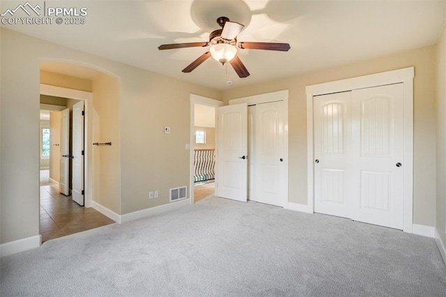 5085 Saxton Hollow Rd, Colorado Springs, CO 80908 - unfurnished bedroom with two closets, carpet floors, arched walkways, and multiple windows