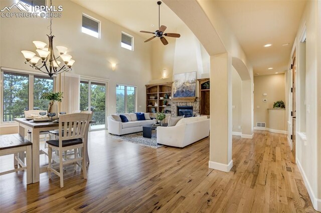 5085 Saxton Hollow Rd, Colorado Springs, CO 80908 - living area with a stone fireplace, light wood-style flooring, a chandelier, arched walkways, and a ceiling fan