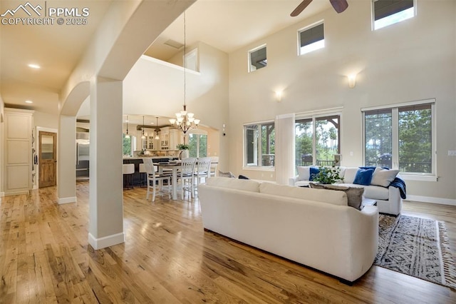5085 Saxton Hollow Rd, Colorado Springs, CO 80908 - living room featuring ceiling fan, light wood-type flooring, arched walkways, and a towering ceiling