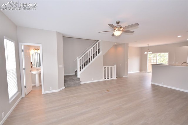 1160 Walters Pt, Monument, CO 80132 - unfurnished living room with a chandelier, light wood finished floors, ceiling fan, stairs, and baseboards
