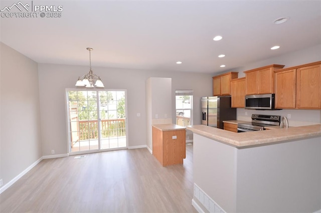 1160 Walters Pt, Monument, CO 80132 - kitchen with stainless steel appliances, light countertops, light wood-style flooring, a chandelier, and a peninsula