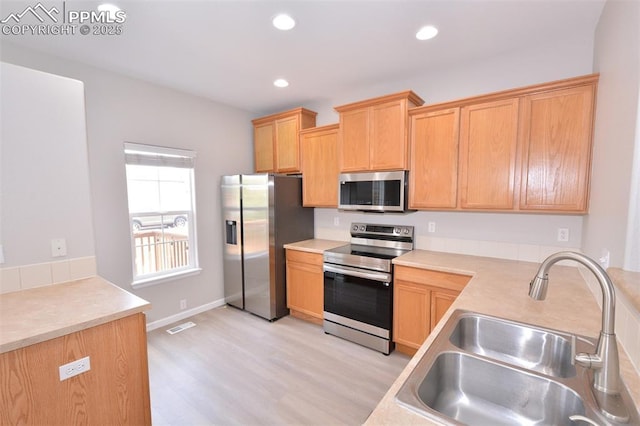 1160 Walters Pt, Monument, CO 80132 - kitchen with appliances with stainless steel finishes, a sink, light wood-style flooring, light countertops, and light brown cabinetry