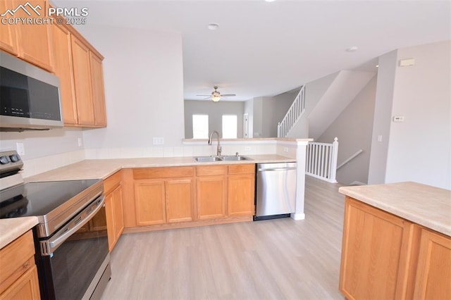 1160 Walters Pt, Monument, CO 80132 - kitchen with stainless steel appliances, a sink, light wood-style floors, a peninsula, and a ceiling fan
