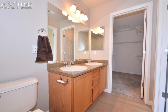 1160 Walters Pt, Monument, CO 80132 - full bathroom featuring double vanity, wood finished floors, toilet, and a walk in closet