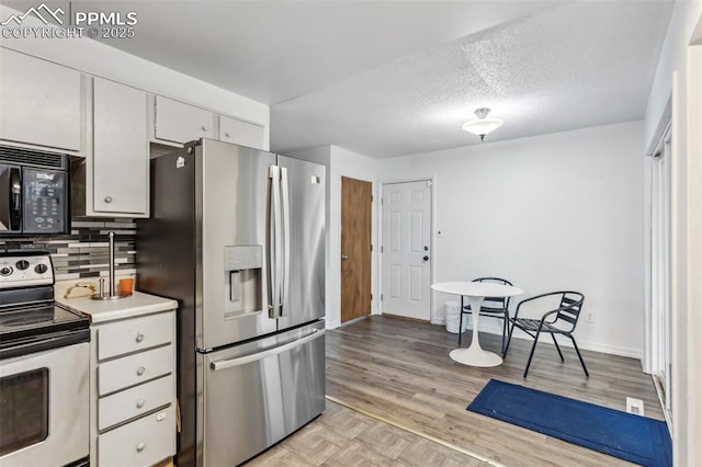 2123 Kodiak Dr, Colorado Springs, CO 80910 - kitchen featuring stainless steel appliances, tasteful backsplash, white cabinetry, light wood-style floors, and light countertops