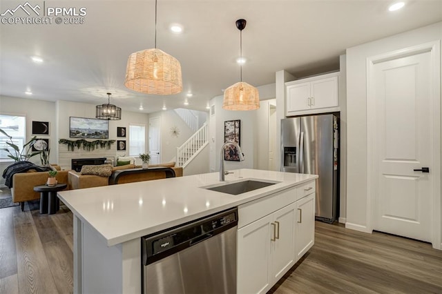 6950 Hidden Cove Ct, Castle Pines, CO 80108 - kitchen with appliances with stainless steel finishes, a sink, dark wood-style floors, a fireplace, and recessed lighting