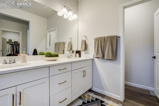 6950 Hidden Cove Ct, Castle Pines, CO 80108 - full bathroom featuring double vanity, wood finished floors, baseboards, and a walk in closet