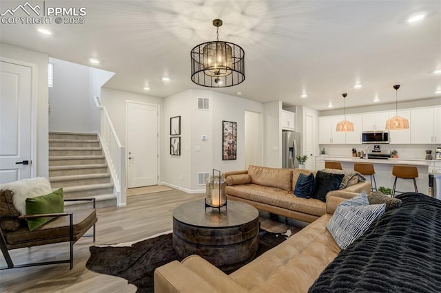 6950 Hidden Cove Ct, Castle Pines, CO 80108 - living room featuring light wood-style flooring, a chandelier, stairs, recessed lighting, and baseboards