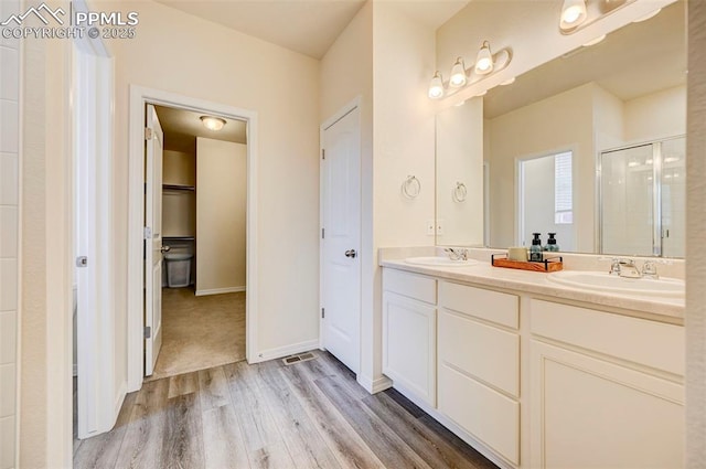 10806 Rolling Peaks Dr, Peyton, CO 80831 - full bathroom featuring a stall shower, double vanity, wood finished floors, a closet, and baseboards