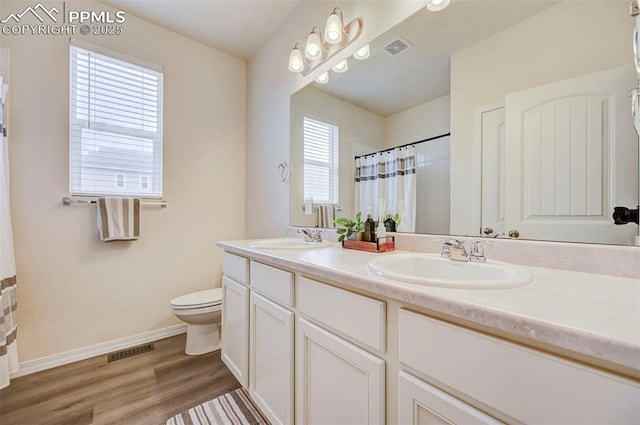 10806 Rolling Peaks Dr, Peyton, CO 80831 - bathroom featuring toilet, double vanity, wood finished floors, a shower with curtain, and baseboards