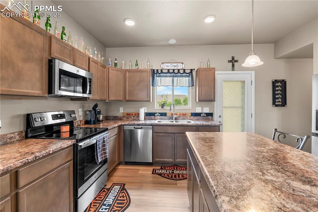 5228 Gannet Ln, Pueblo, CO 81008 - kitchen featuring appliances with stainless steel finishes, light wood finished floors, pendant lighting, recessed lighting, and brown cabinetry