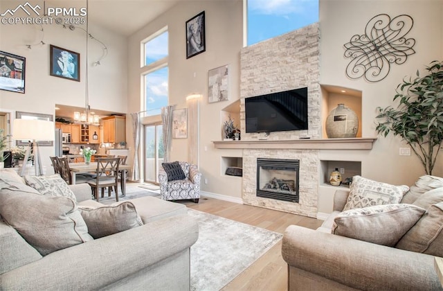 2582 Indian Hills Grv, Colorado Springs, CO 80907 - living area with a fireplace, a high ceiling, a chandelier, light wood-style floors, and baseboards