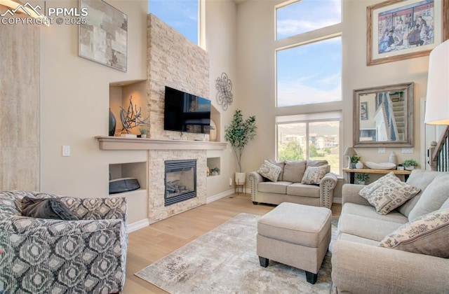 2582 Indian Hills Grv, Colorado Springs, CO 80907 - living area with a fireplace, wood finished floors, a towering ceiling, and baseboards