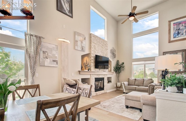 2582 Indian Hills Grv, Colorado Springs, CO 80907 - living room with ceiling fan, a towering ceiling, a glass covered fireplace, wood finished floors, and baseboards