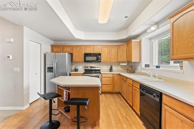 2237 Stepping Stones Way Unit C, Colorado Springs, CO 80904 - kitchen featuring black appliances, a sink, a tray ceiling, a kitchen island, and a breakfast bar