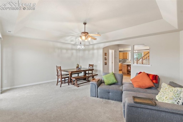 2237 Stepping Stones Way Unit C, Colorado Springs, CO 80904 - living room featuring arched walkways, a raised ceiling, a ceiling fan, and light colored carpet