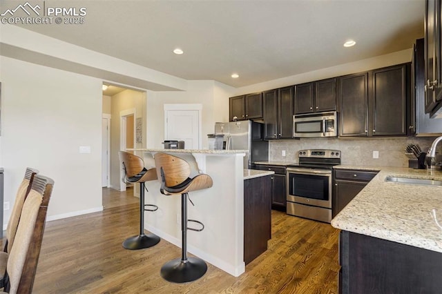10208 Abrams Dr, Colorado Springs, CO 80925 - kitchen with stainless steel appliances, a kitchen breakfast bar, dark wood finished floors, dark brown cabinets, and recessed lighting