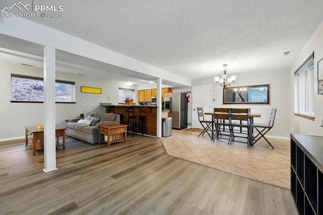 4840 Pikes Peak Hwy, Cascade, CO 80809 - living area featuring plenty of natural light, light wood-style floors, a textured ceiling, a chandelier, and baseboards