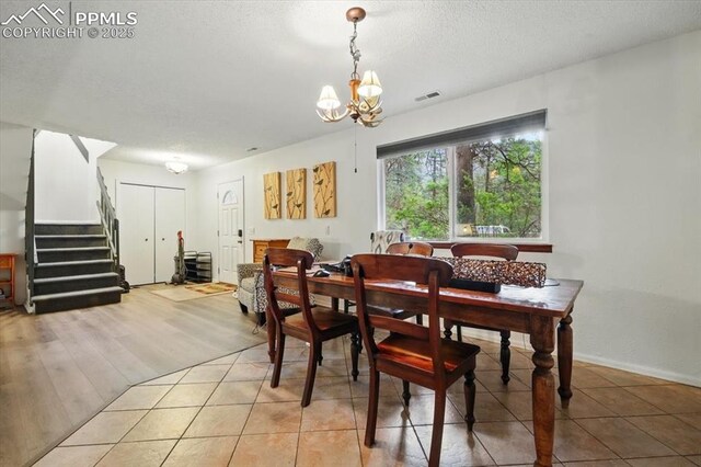 4840 Pikes Peak Hwy, Cascade, CO 80809 - dining room with a chandelier, stairway, a textured ceiling, and light tile patterned flooring