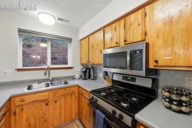 4840 Pikes Peak Hwy, Cascade, CO 80809 - kitchen featuring appliances with stainless steel finishes, a sink, light countertops, a textured ceiling, and brown cabinetry
