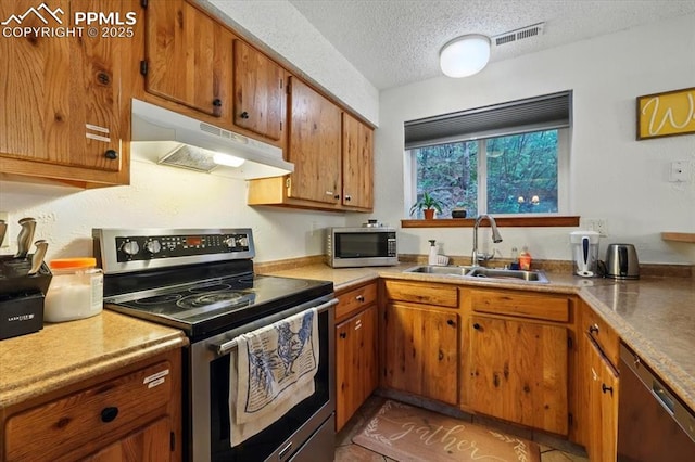 4840 Pikes Peak Hwy, Cascade, CO 80809 - kitchen featuring under cabinet range hood, appliances with stainless steel finishes, a sink, brown cabinets, and a textured ceiling
