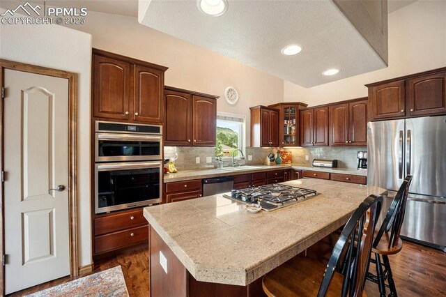 20280 Melanie Ann Ct, Monument, CO 80132 - kitchen with appliances with stainless steel finishes, a sink, a breakfast bar area, light countertops, and decorative backsplash