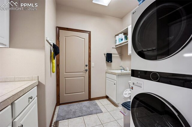 20280 Melanie Ann Ct, Monument, CO 80132 - laundry area featuring estacked washer and dryer, cabinet space, baseboards, and light tile patterned floors