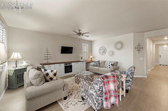 13138 Stoney Meadows Way, Peyton, CO 80831 - living room with baseboards, light wood-style floors, a ceiling fan, and a fireplace