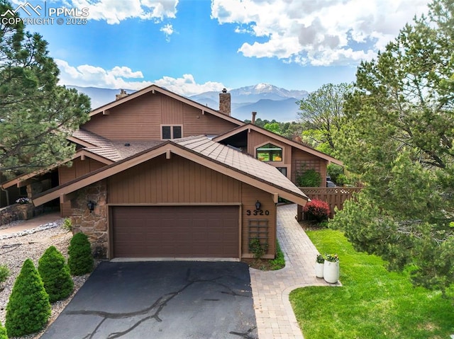 3320 Camels Ridge Ln, Colorado Springs, CO 80904 - mid-century modern home with a chimney, asphalt driveway, a mountain view, a garage, and stone siding