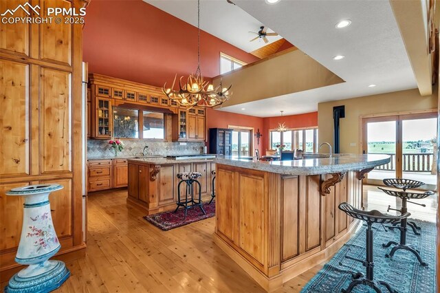 15958 Shadow Mountain Ranch Rd, Larkspur, CO 80118 - kitchen featuring a kitchen island with sink, a breakfast bar area, light wood-style floors, a chandelier, and a sink