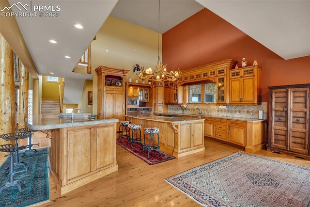 15958 Shadow Mountain Ranch Rd, Larkspur, CO 80118 - kitchen featuring a towering ceiling, stainless steel appliances, light wood finished floors, a kitchen island, and a breakfast bar area