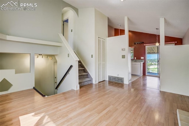 6430 Chantilly Pl, Colorado Springs, CO 80922 - unfurnished living room with high vaulted ceiling, wood finished floors, stairway, and arched walkways
