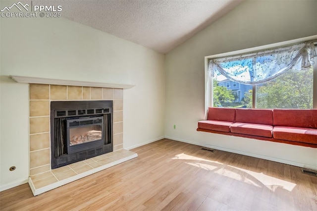 6430 Chantilly Pl, Colorado Springs, CO 80922 - unfurnished living room featuring vaulted ceiling, wood finished floors, a textured ceiling, and a tile fireplace