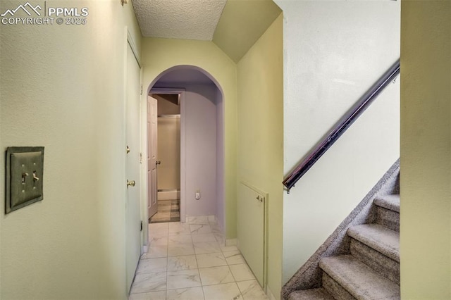 6430 Chantilly Pl, Colorado Springs, CO 80922 - corridor featuring arched walkways, light marble finish floors, a textured ceiling, and stairs