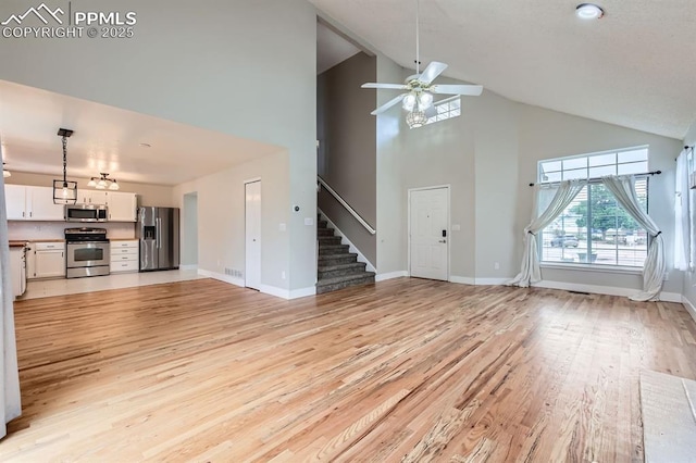 9412 Dew Drop Ct, Colorado Springs, CO 80925 - unfurnished living room featuring high vaulted ceiling, light wood-type flooring, ceiling fan, stairs, and baseboards