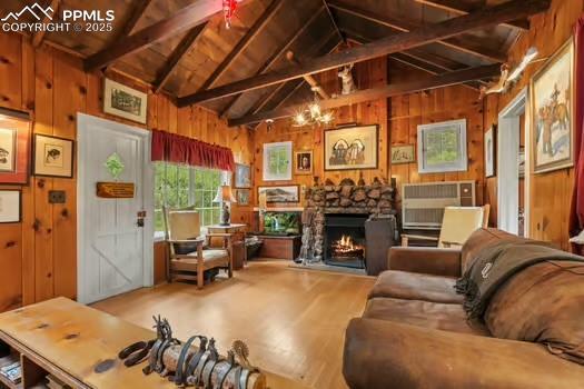6015 Sioux Trl, Cascade, CO 80809 - living room with wood walls, a fireplace, wood finished floors, wooden ceiling, and a chandelier