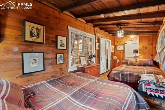 6015 Sioux Trl, Cascade, CO 80809 - bedroom featuring wood ceiling with exposed beams and wooden walls