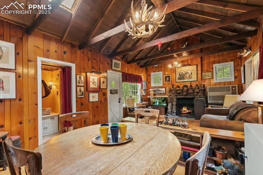 6015 Sioux Trl, Cascade, CO 80809 - dining area with wood walls, a stone fireplace, a chandelier, and wooden ceiling