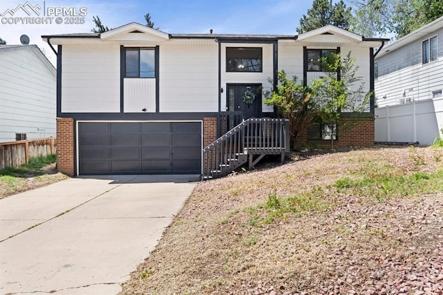 527 W Columbia St, Colorado Springs, CO 80907 - bi-level home with brick siding, concrete driveway, and a garage