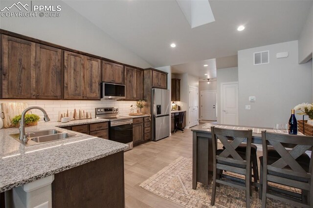 529 Brecken Ct Unit A, Woodland Park, CO 80863 - kitchen with stainless steel appliances, a sink, tasteful backsplash, dark brown cabinetry, and lofted ceiling
