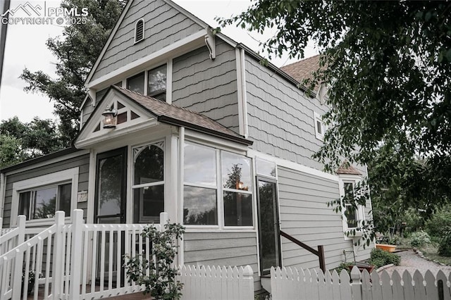 817 Swope Ave, Colorado Springs, CO 80909 - view of home's exterior with a shingled roof and a sunroom